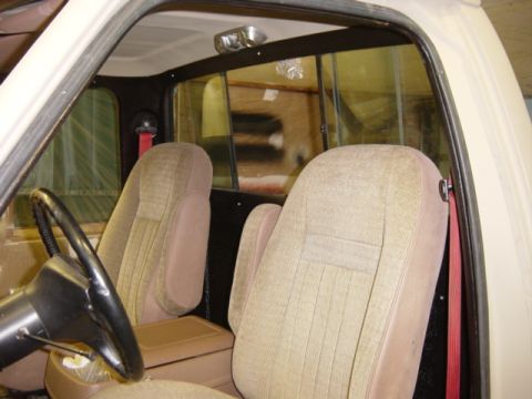 1991 Ford Bronco - The interior of this vehicle features tan cloth bucket seats and a dark steering wheel, with yellow-tinted rear windows.