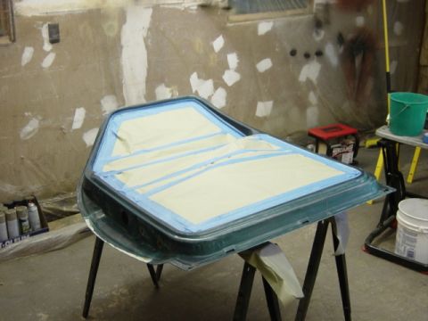 1991 Ford Bronco - A car door is prepped with masking tape for painting in a workshop setting.