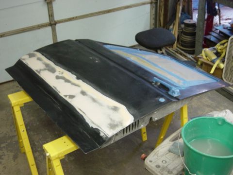 1991 Ford Bronco - A car door is being prepped for paint, with body filler applied and masking tape in place.