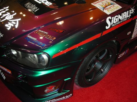 1998 Ford Crown Victoria - Front quarter of a green color-shifting coupe with black SSR wheels and Signal decals displayed on a red carpet.