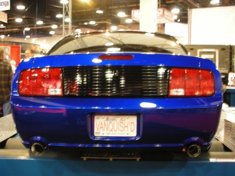 1998 Ford Crown Victoria - Rear view of a blue Ford Mustang coupe with dual exhaust and an Alberta license plate reading VANQUISH'D.