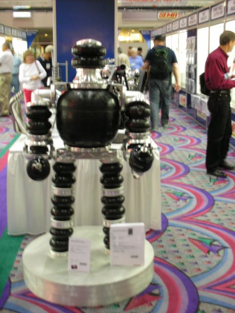 1998 Ford Crown Victoria - vertical display of black air-suspension bags and components mounted on a pedestal in a convention hall aisle.