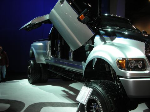 1998 Ford Crown Victoria - lifted silver Ford F-650 truck with a vertical lambo-style door open, shown on a lit display floor.