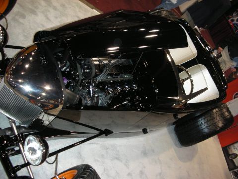 1998 Ford Crown Victoria - Looking down into a black custom hot rod, its chrome engine, white tuck-and-roll seats, and polished headlight are on display.
