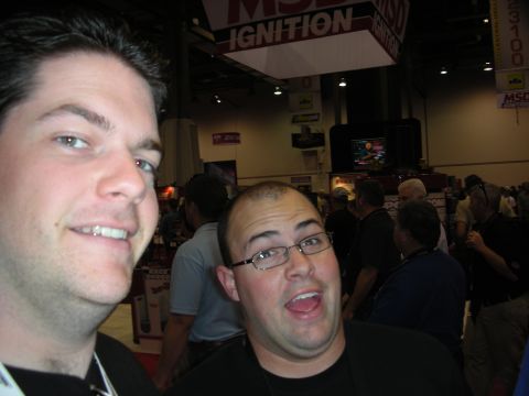 1998 Ford Crown Victoria - Two young men mug for a close-up photo beneath a red MSD Ignition banner in a crowded convention hall.