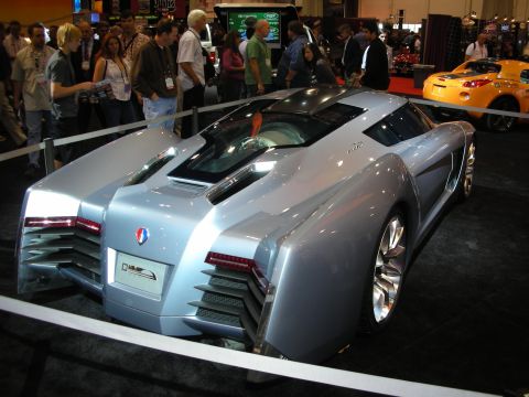 1998 Ford Crown Victoria - futuristic silver-blue wedge-shaped concept supercar with angular bodywork is displayed behind ropes at an auto show.