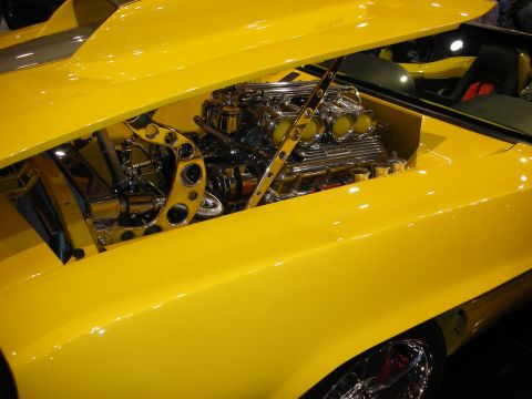 1998 Ford Crown Victoria - highly polished engine with stack injection fills the bay beneath the raised hood of a yellow custom car.