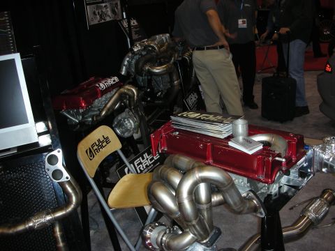 1998 Ford Crown Victoria - Display engines with red valve covers and coiled stainless steel exhaust manifolds at a Full Race trade show booth.