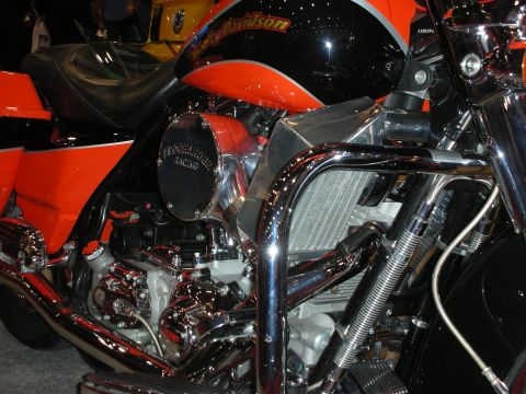 1998 Ford Crown Victoria - Close-up of an orange and black custom Harley-Davidson bagger showing chrome engine cases and crash bars.