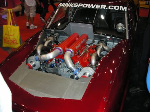 1998 Ford Crown Victoria - twin-turbo engine with a red intake manifold sits in a candy-red car under a Bankspower.com banner.
