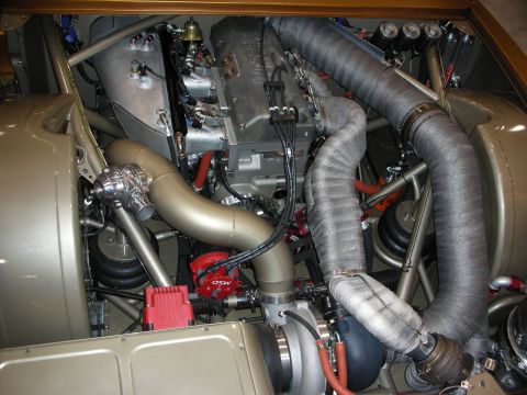 1998 Ford Crown Victoria - tightly packed gold-bodied engine bay with MSD ignition wires, heat-wrapped headers, and dual turbochargers.
