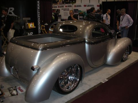 1998 Ford Crown Victoria - silver chopped coupe-style hot rod with chrome billet wheels displayed at a Legens Hot Rods trade show booth.
