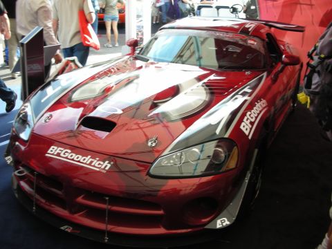 1998 Ford Crown Victoria - red and silver Dodge Viper coupe with BFGoodrich livery and a rear wing on display in a crowded show hall.