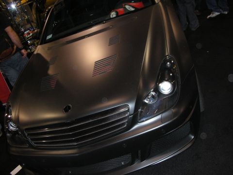 1998 Ford Crown Victoria - Close front view of a matte black Mercedes-Benz with a louvered vented hood, mesh grille and projector headlight.