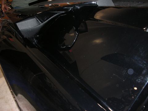1998 Ford Crown Victoria - glossy black custom car body panel with a sculpted air scoop and mesh insert, photographed indoors.