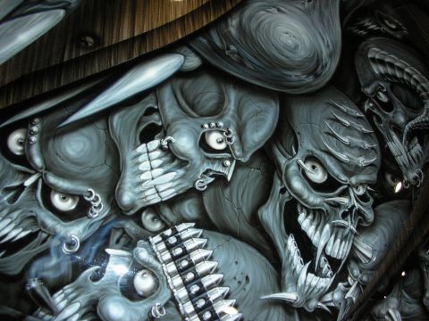 1998 Ford Crown Victoria - Close-up of an airbrushed mural of snarling grey skulls and demon faces painted across a glossy automotive body panel.