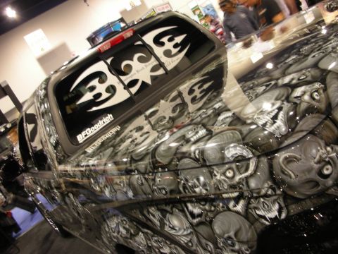 1998 Ford Crown Victoria - Rear three-quarter view of a custom truck with tribal window graphics and grey skull airbrushing under indoor show lighting.
