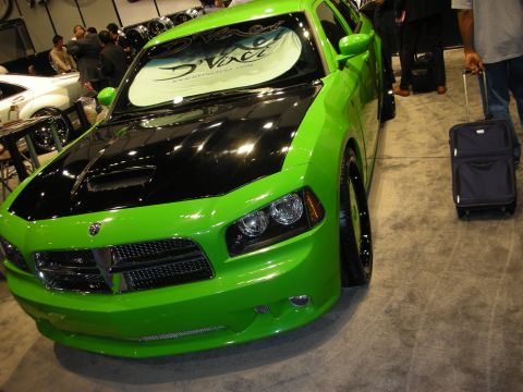 1998 Ford Crown Victoria - bright green Dodge Charger with a black hood and tinted windshield banner on display at an indoor car show.