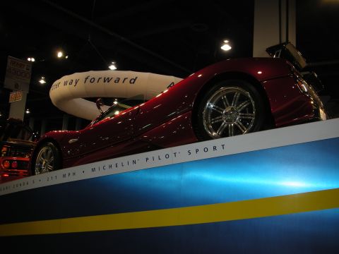 1998 Ford Crown Victoria - A red sports car is displayed with text indicating Michelin Pilot Sport tires and a top speed of 211 MPH.