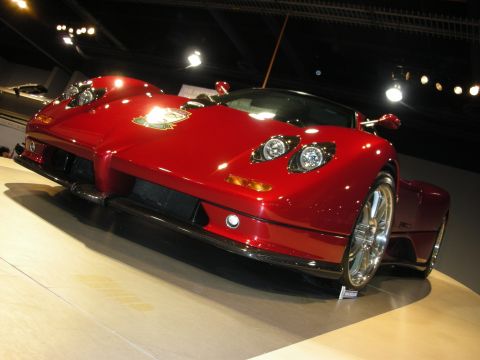 1998 Ford Crown Victoria - A bright red, low-slung sports car is displayed indoors under bright lights.