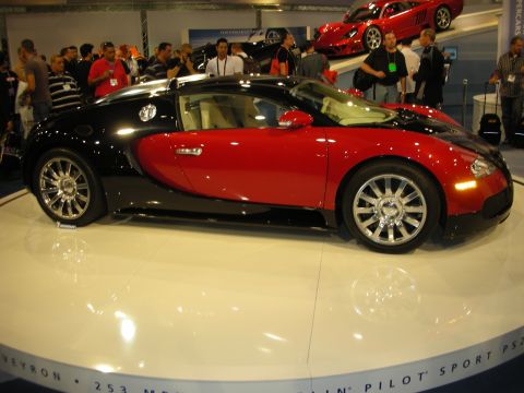 1998 Ford Crown Victoria - A two-tone red and black Bugatti Veyron is displayed on a white platform with people in the background.