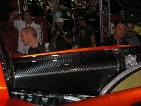 1998 Ford Crown Victoria - The engine bay of a custom car is shown, a carbon fiber cover and vibrant orange exterior paint.