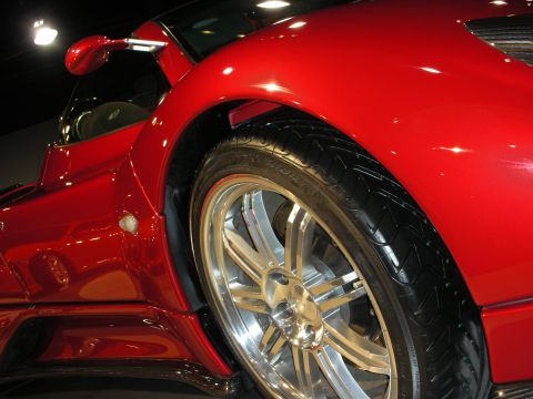 1998 Ford Crown Victoria - Close-up view of a red sports car's wheel and fender, highlighting its design and polished finish.