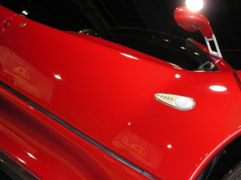 1998 Ford Crown Victoria - Close-up of a red sports car door, showing the Pagani emblem and a side mirror.