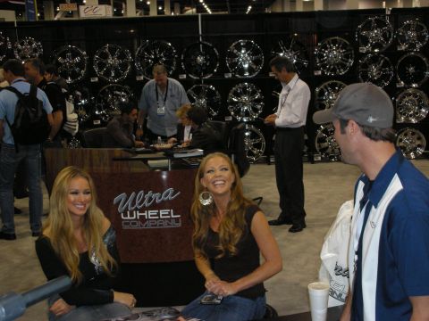 1998 Ford Crown Victoria - A trade show booth for Ultra Wheel Company features numerous chrome wheels and several attendees interacting.
