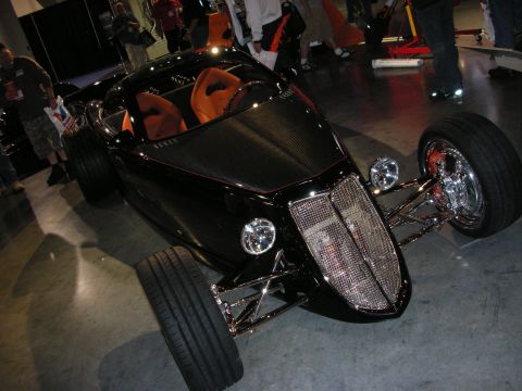 1998 Ford Crown Victoria - A custom hot rod with a distinctive chrome grille and orange racing seats is displayed indoors.