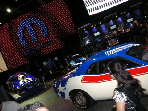 1998 Ford Crown Victoria - A Mopar display features two distinctively decorated race cars under a large illuminated Mopar logo.