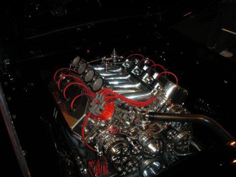 1998 Ford Crown Victoria - polished V8 with a tunnel-ram intake, multiple carburetors and bright red spark-plug wires gleams in a dim engine bay.