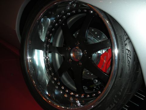 1998 Ford Crown Victoria - large black six-spoke wheel with polished lip, red multi-piston caliper and a wide 335-section tire on a silver car.