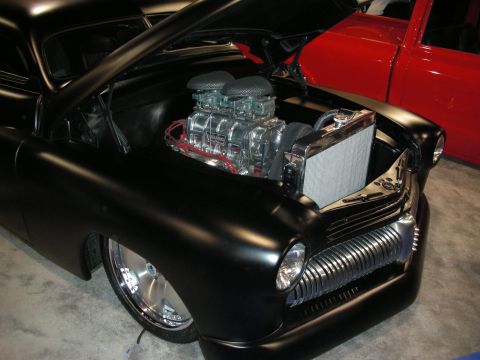 1998 Ford Crown Victoria - matte black chopped custom car with its hood open shows a supercharged V8 with dual carbs and a polished radiator.