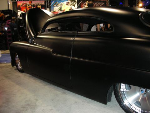 1998 Ford Crown Victoria - Side profile of a matte black chopped and lowered custom coupe with polished wheels on display at an indoor show.