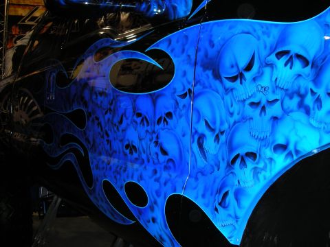 1998 Ford Crown Victoria - vehicle body panel airbrushed with a dense field of blue skulls inside black tribal flames at an indoor show.