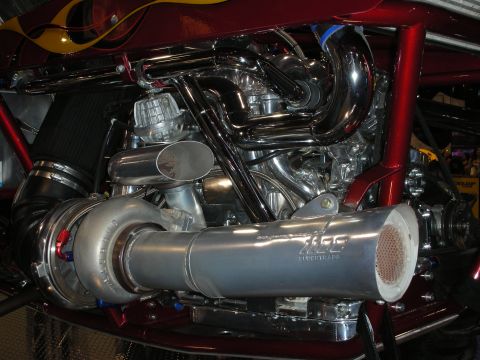 1998 Ford Crown Victoria - heavily chromed twin-turbo engine fills a maroon, flame-painted engine bay with polished intercooler piping and tubular framework.