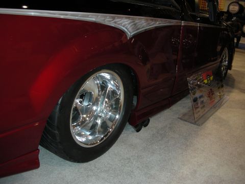 1998 Ford Crown Victoria - Close-up of a lowered deep-maroon vehicle's side showing a polished billet wheel, low-profile tire, and ground-scraping body.