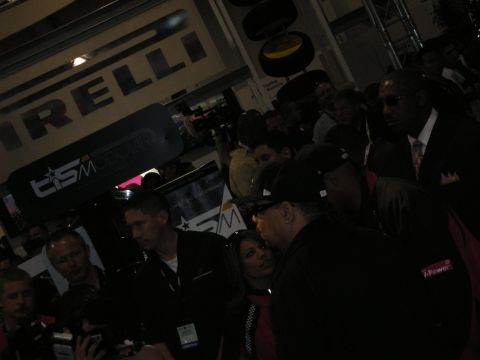 1998 Ford Crown Victoria - dimly lit crowd of attendees gathers near a Pirelli tire display at a TIS-branded booth during an indoor automotive event.