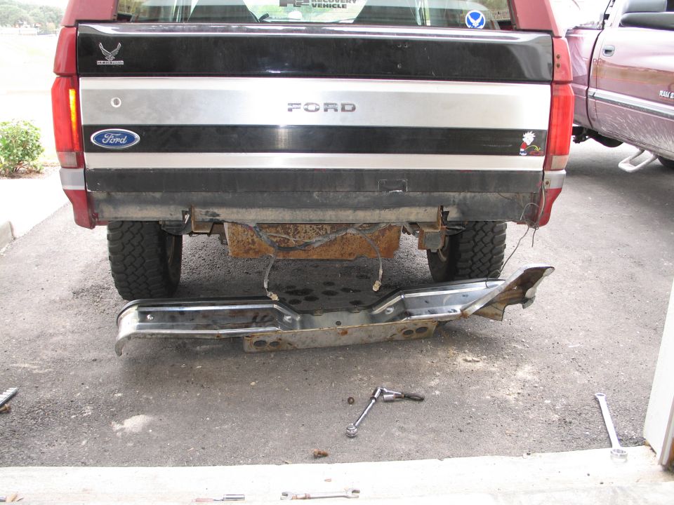 Detached rear bumper of a 1995 Ford Bronco with tools on the ground