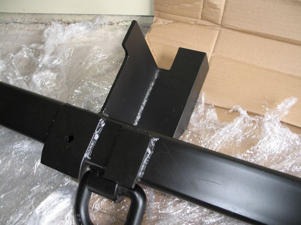Black metal tow hitch receiver with a D-ring attachment, wrapped in plastic