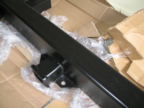 1995 Ford Bronco - A close-up view of a black rear bumper assembly, likely a replacement part, situated on a bed of cardboard packaging.