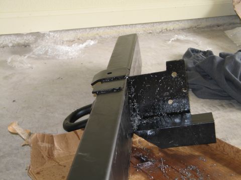 1995 Ford Bronco - Close-up of a black rear bumper section with a tow hitch loop and mounting bracket, resting on cardboard.