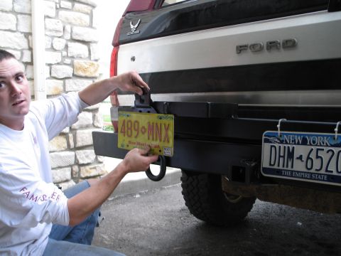 1995 Ford Bronco - A man attaches a New Mexico license plate to the rear bumper of a Ford Bronco.