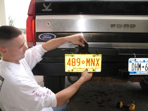 1995 Ford Bronco - A person installs a New Mexico license plate onto the rear bumper of a 1995 Ford Bronco.