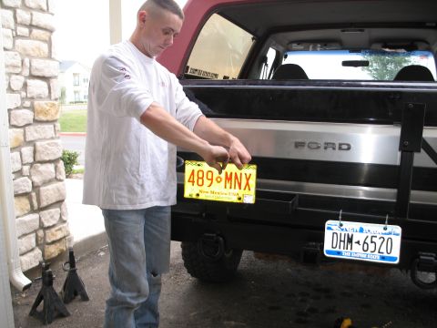 1995 Ford Bronco - Man installs a New Mexico license plate on the rear of a 1995 Ford Bronco.