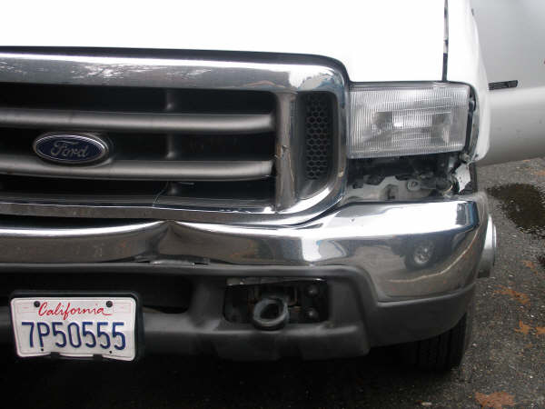 Ford truck front end with dented chrome bumper and damaged headlight