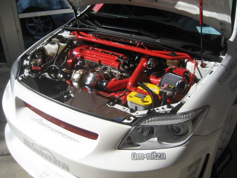1998 Ford Crown Victoria - Customized engine bay with a prominent turbocharger and red accents, a "üm-nitza" sticker on the headlight.