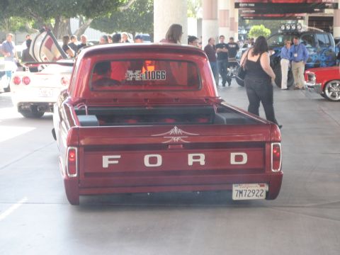 1998 Ford Crown Victoria - A red 1967 Ford pickup truck is parked outdoors, seen from the rear with other vehicles nearby.