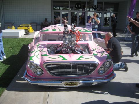 1998 Ford Crown Victoria - A heavily modified pink hot rod with an exposed engine and custom flame paint is displayed outdoors.